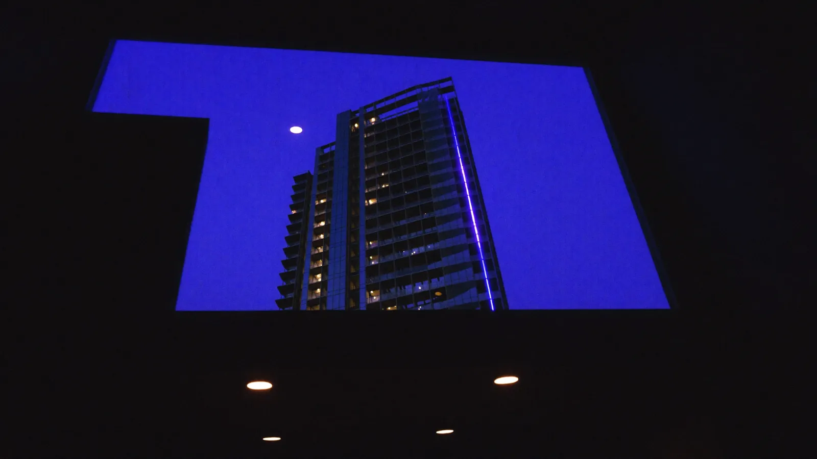 A modern glass tower at blue hour under an indigo sky.