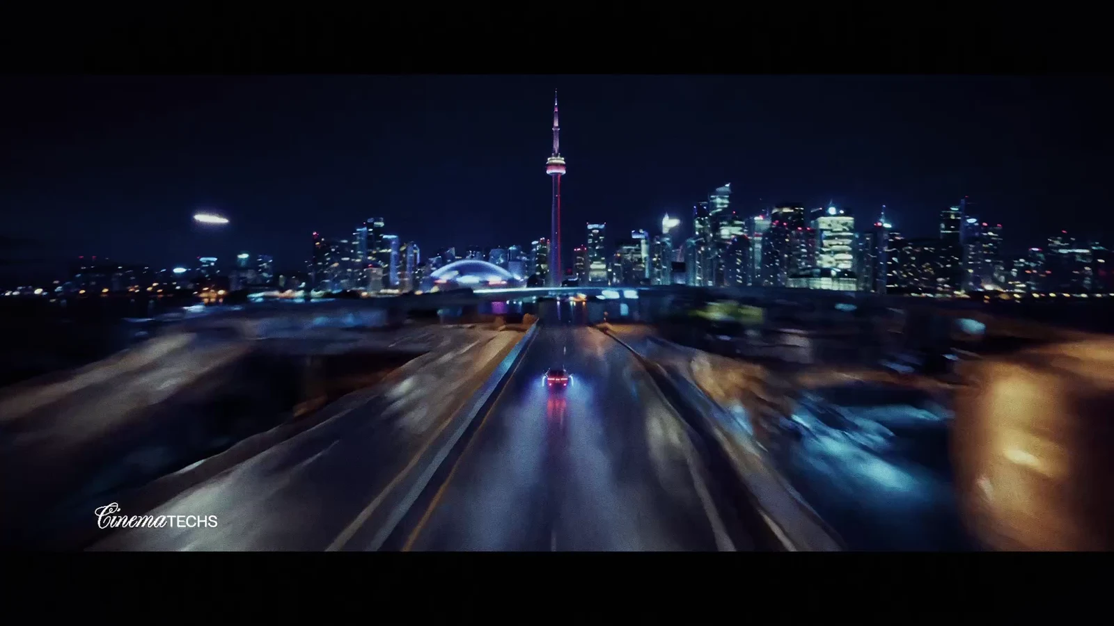 Chrome concept car in motion, kicking up spray with a blue underglow against the night skyline.