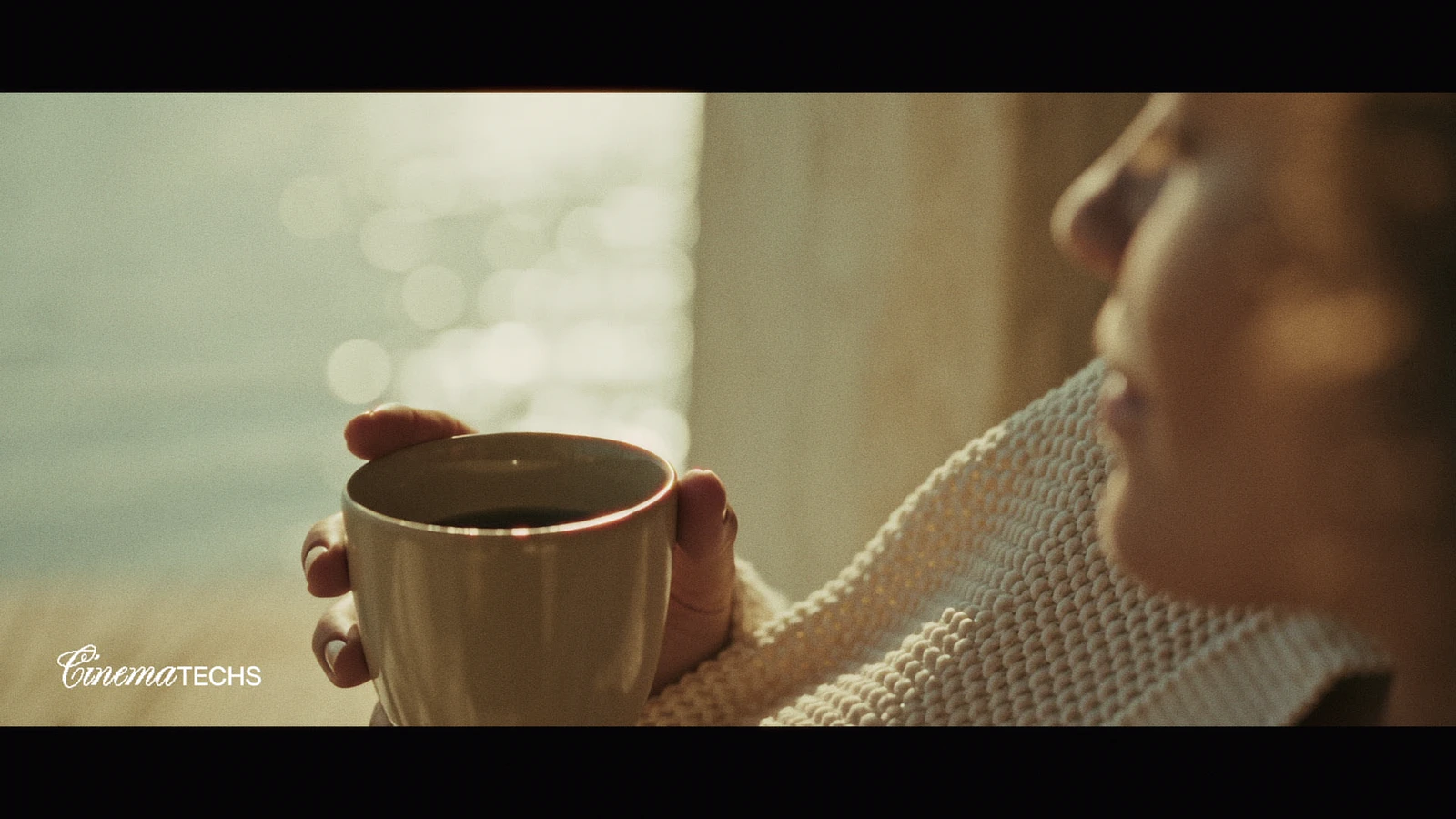 A woman in profile holding a cup in warm side light, freckles and skin texture reading as real.