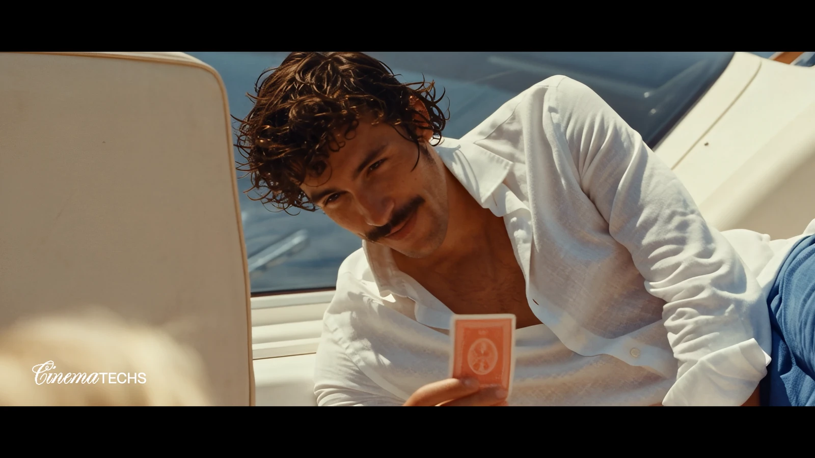 A man on deck in open linen, hair, skin and the weave of the cloth reading as real.